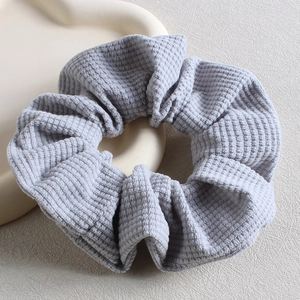 Detail of light blue waffle texture fabric scrunchie on a beige tray for hair accessory
