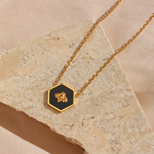 Macro shot of gold bee relief on black hexagonal pendant with golden chain