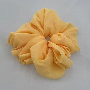 Close-up of a soft yellow chiffon scrunchie showing detailed fabric texture and pleats