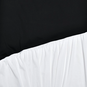 Macro shot of black and white color block dress showing fine textile texture and pleated detail