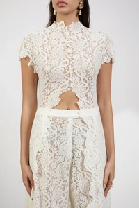 Macro shot of intricate floral lace texture and waist cutout on white cardigan top