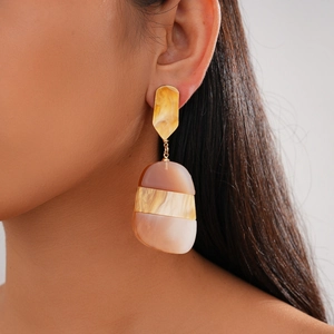 Close-up of geometric acetate drop earrings featuring amber textures and marble patterns