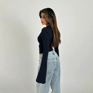 Detail of slim fit navy blue long sleeve top with lace trim and light blue jeans
