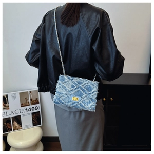 Détail du sac bandoulière en jean bleu clair avec motif matelassé et bandoulière dorée