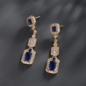 Detail of luxury geometric earrings featuring blue crystals and micro-pave cubic zirconia