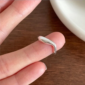 Close-up of minimalist sterling silver wave ring with a polished finish worn on a finger
