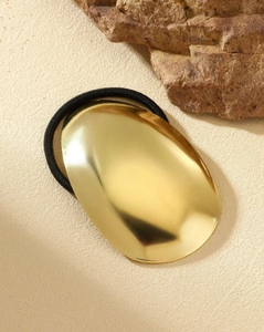 Macro shot of black elastic hair tie with a polished gold oval metal buckle ornament