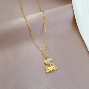 Detail of bear pendant with mother of pearl and Love engraved heart on gold chain