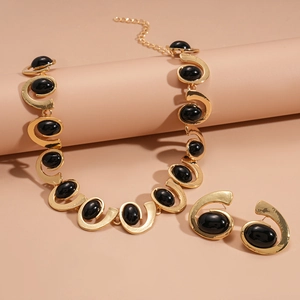 Vintage gold necklace and earrings set with black oval gemstones and spiral design