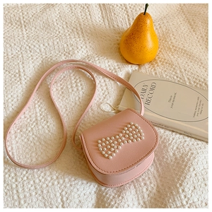 Close-up of pink girls mini crossbody bag with cute white pearl bowknot pattern detail