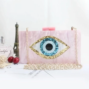 Detail of pink marble acrylic clutch with blue evil eye pattern and gold chain strap
