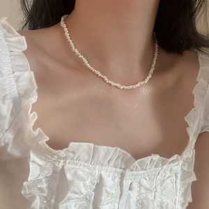 Close-up of elegant small freshwater pearl necklace on neck with white ruffle dress