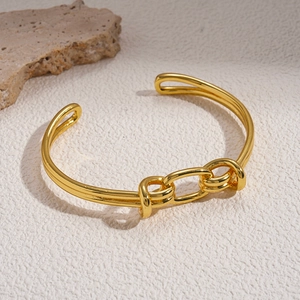 Polished 18K gold plated oval open bangle with chain knot design on marble background