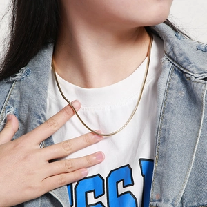 Close-up of golden square snake bone chain necklace worn by a model on the neck