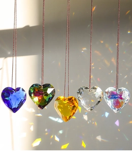 Rainbow light reflecting through five heart-shaped crystal prisms on strings