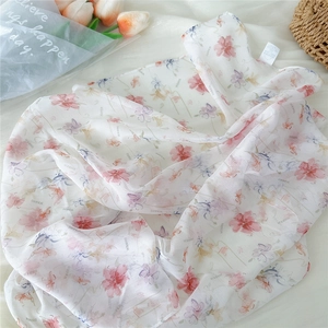 Detail of floral chiffon scarf with pink flowers and Dream text in a woven basket