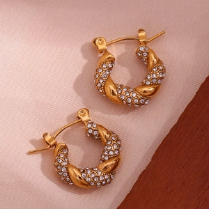 Macro detail of twisted 18K gold-plated hoop earrings with sparkling pave zircon settings