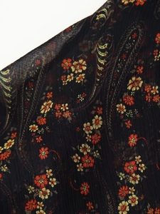 Close-up detail of black chiffon fabric with vintage red floral and paisley prints