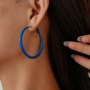 Close-up side view of a model wearing large Klein blue geometric circular hoop earrings