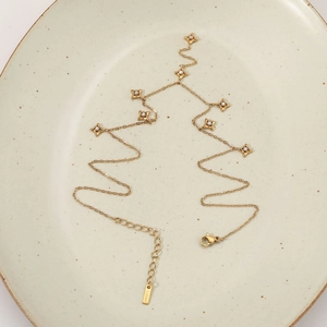 Gold stainless steel Y-shaped necklace with star pendants on white ceramic plate