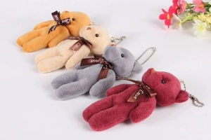 Detailed view of plush bear charms in orange, beige, grey, and burgundy with metal chains