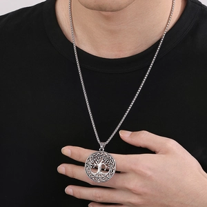 Close-up of a silver Tree of Life pendant with chain worn by a male model