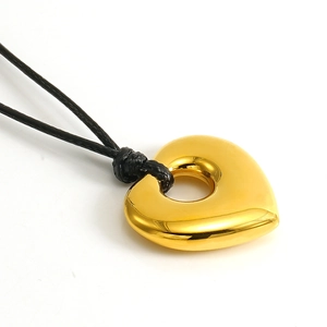 Golden hollow heart pendant on black wax rope necklace, top-down view with metallic shine