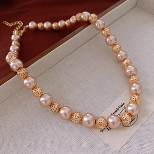 Detail of pink pearl necklace with hollow gold beads and lobster clasp closure