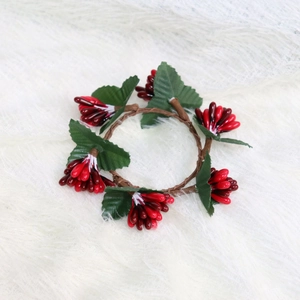 Detailed close-up of Christmas napkin ring with red berries and green leaves on white faux fur