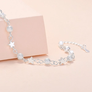 Elegant silver planet bracelet featuring frosted beads and stars on a soft pink background