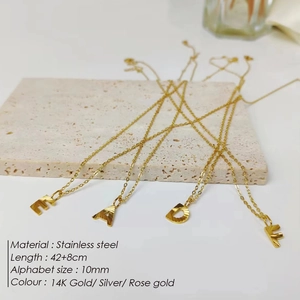 Golden stainless steel initial necklaces with 14K gold alphabet pendants on stone display