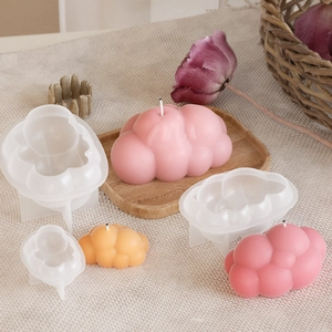 Vista macro degli stampi in silicone a nuvola e candele rifinite in toni pastello
