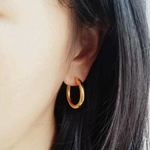 Minimalist golden hoop earrings for women with polished mirror finish on a model