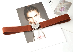 Détail d'une boucle en cœur argentée sur une ceinture élastique marron sur magazine