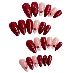 Long almond press-on nails in deep red and nude pink with red star patterns