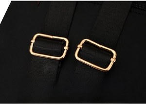 Detail of adjustable golden metal buckles on black nylon straps of a travel backpack