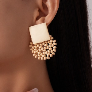 Detailansicht eines beigen geometrischen Holzohrrings an einem Model für Boho-Stil