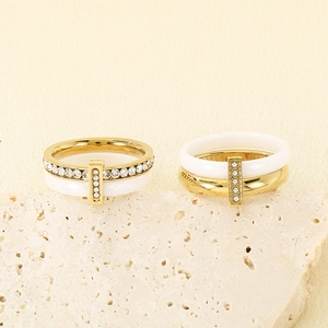 Polished white ceramic rings with gold steel and zircon inlay on a textured stone