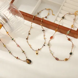 Three boho-style handmade stone necklaces with tiger eye and agate pendants on a wood tray