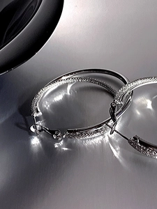 Detailed macro view of silver double-layered hoop earrings with frosted matte texture