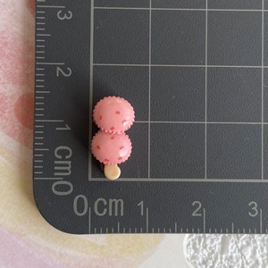 Mini breloque glace rose en résine mesurant 2,5 cm sur un tapis de coupe gradué