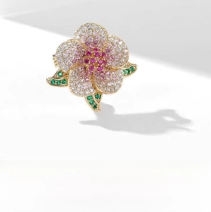 Close-up of pink and white crystal flower brooch with emerald green leaf stones