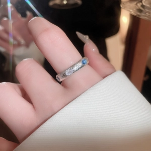 Detailed view of silver wave ring with blue and white oval gemstones on a hand