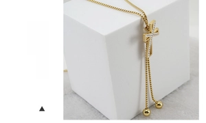 Macro detail of 18K gold-plated cross pendant with sparkling crystal inlay and beads