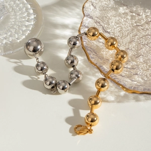 Vue détaillée de bracelets en perles de laiton or et argent sur un support en verre