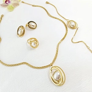 Detail of gold jewelry set with faux pearls including necklace, earrings and ring on white