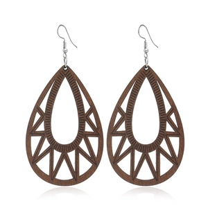 Détail de boucles d'oreilles en bois en forme de goutte avec motifs géométriques creux