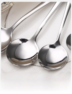 Macro shot of polished stainless steel round spoons on a ceramic plate detail