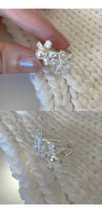 Detailed view of silver flower ring with pearl on soft white knit fabric