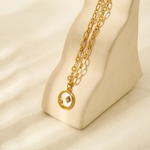 Close-up of 18K gold-plated necklace featuring double chains and shell sun moon pendant
